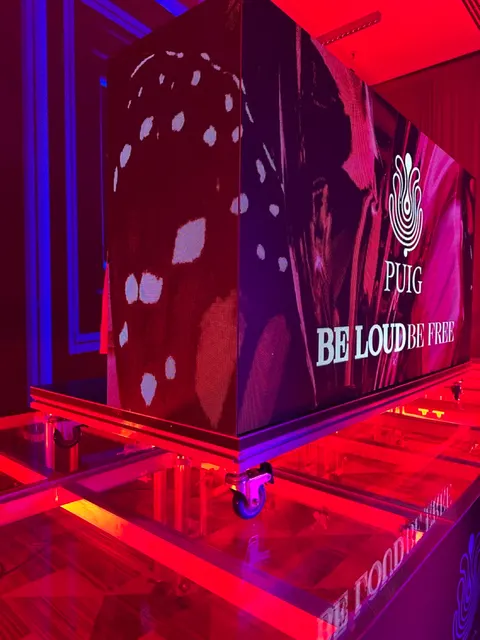 PUIG - Be Loud Be Free · Cubo con frente LED sobre tarima con ruedas